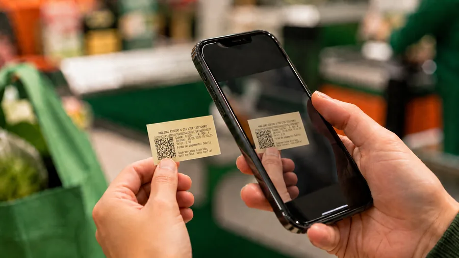 Cliente segurando o cupom reduzido, do tamanho de um cartão, e escaneando o QR Code com o celular